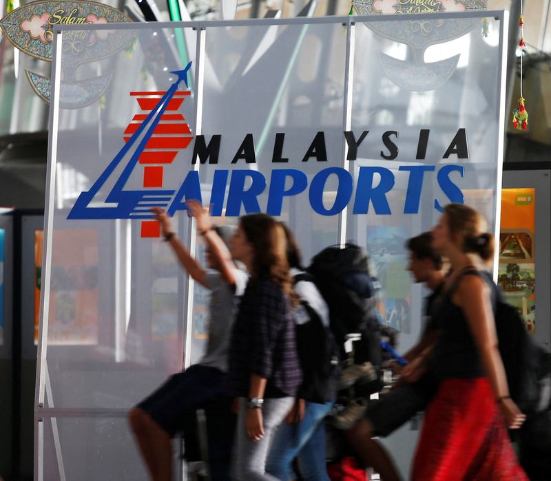 © Reuters. FILE PHOTO: Travellers push their trolley past a logo of Malaysia Airports at the departure hall of Kuala Lumpur International Airport in Sepang, outside Kuala Lumpur August 26, 2013. REUTERS/Bazuki Muhammad/File Photo