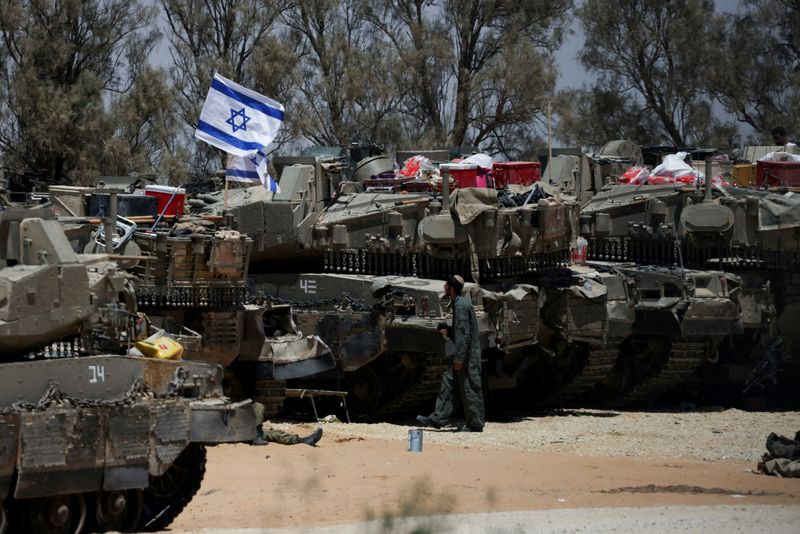 © Reuters. FILE PHOTO: An Israeli soldier walks near military vehicles, amid the ongoing conflict between Israel and the Palestinian Islamist group Hamas, near Israel's border with Gaza in southern Israel, May 29, 2024. REUTERS/Ronen Zvulun/File Photo