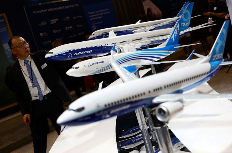 © Reuters. FILE PHOTO: A man passes Boeing model planes on display at the Singapore Airshow at Changi Exhibition Centre in Singapore February 20, 2024. REUTERS/Edgar Su/File Photo