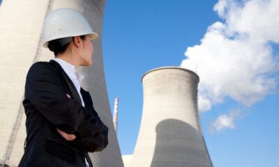 A person in a hard hat looking up at a nuclear power plant.