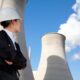 A person in a hard hat looking up at a nuclear power plant.