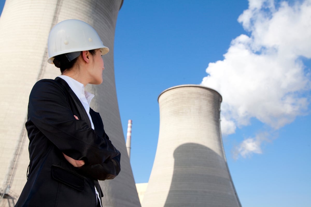 A person in a hard hat looking up at a nuclear power plant.