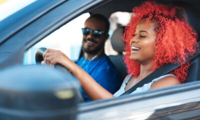 Two people smiling in the front seats of a car.