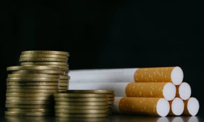 A pile of coins next to a bunch of cigarettes.