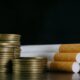 A pile of coins next to a bunch of cigarettes.