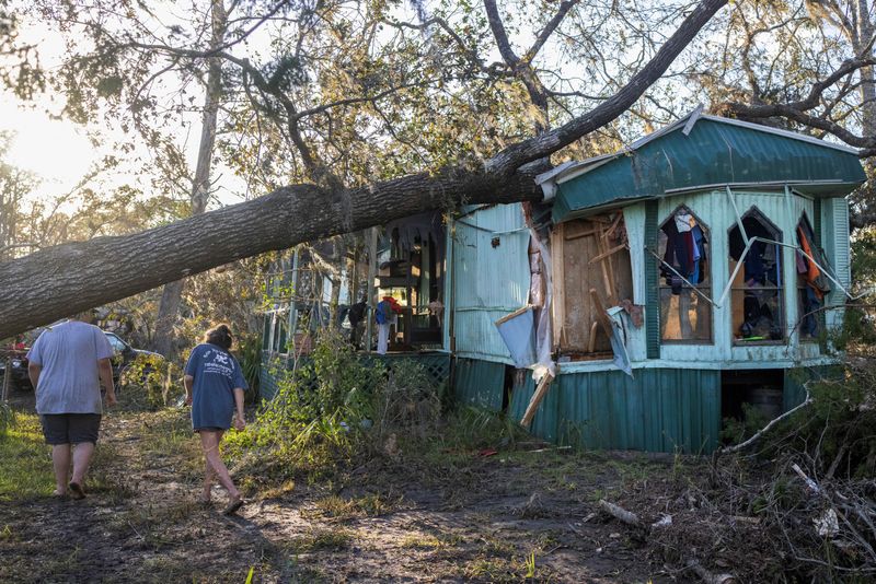 © Reuters. Nash Harris and his mother Alicia walk towards the home where they had been living to try and find some salvageable clothing after Hurricane Helene made landfall in Steinhatchee, Florida, U.S., September 27, 2024. REUTERS/Kathleen Flynn