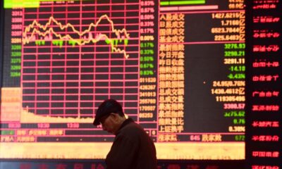 © Reuters. A man is seen against an electronic board showing stock information at a brokerage house in Fuyang, Anhui province, China March 16, 2018. REUTERS/Stringer/File Photo