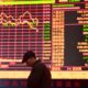 © Reuters. A man is seen against an electronic board showing stock information at a brokerage house in Fuyang, Anhui province, China March 16, 2018. REUTERS/Stringer/File Photo