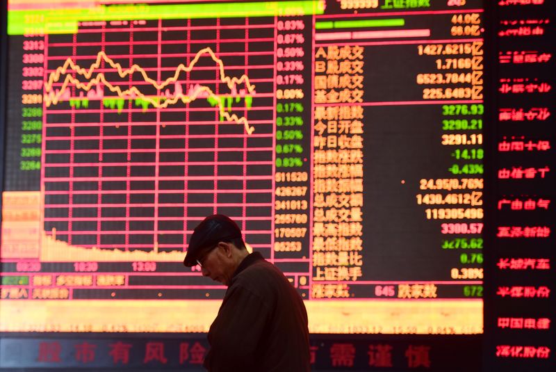 © Reuters. A man is seen against an electronic board showing stock information at a brokerage house in Fuyang, Anhui province, China March 16, 2018. REUTERS/Stringer/File Photo